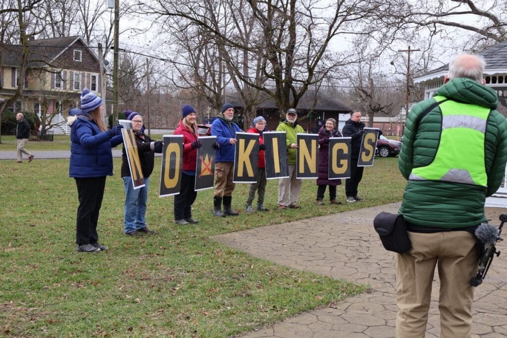 Protesters holding 'NO KINGS' signs outdoors