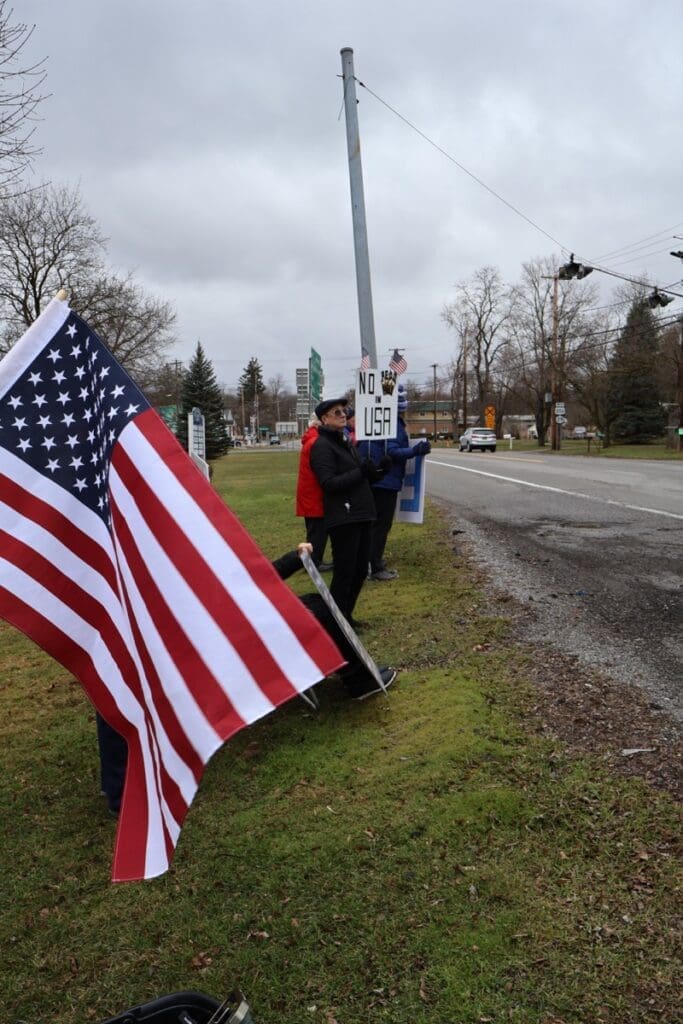 People holding American flags during roadside demonstration