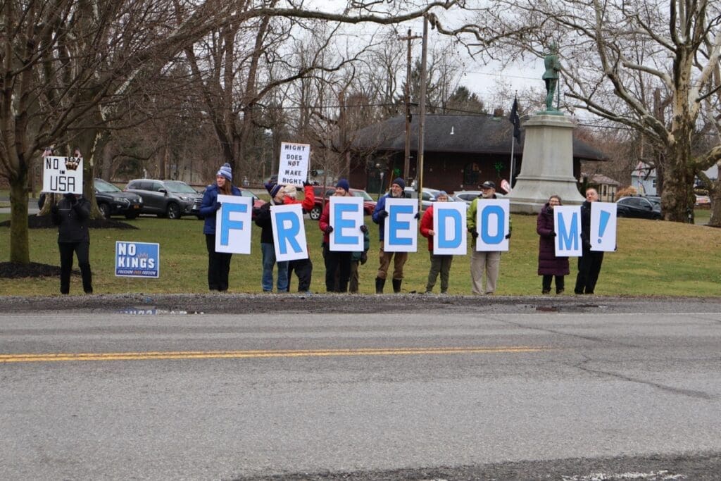 Protesters holding large letters spelling FREEDOM outdoors