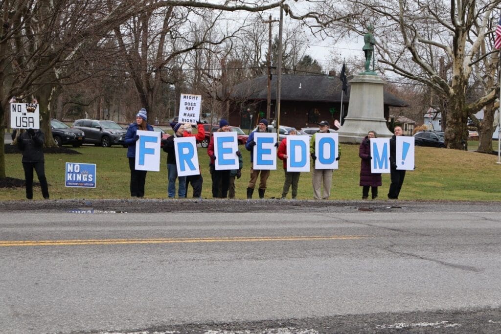 Protesters holding FREEDOM letters near park statue
