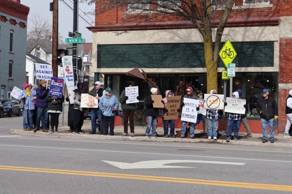 Protesters holding pro-democracy signs on city sidewalk