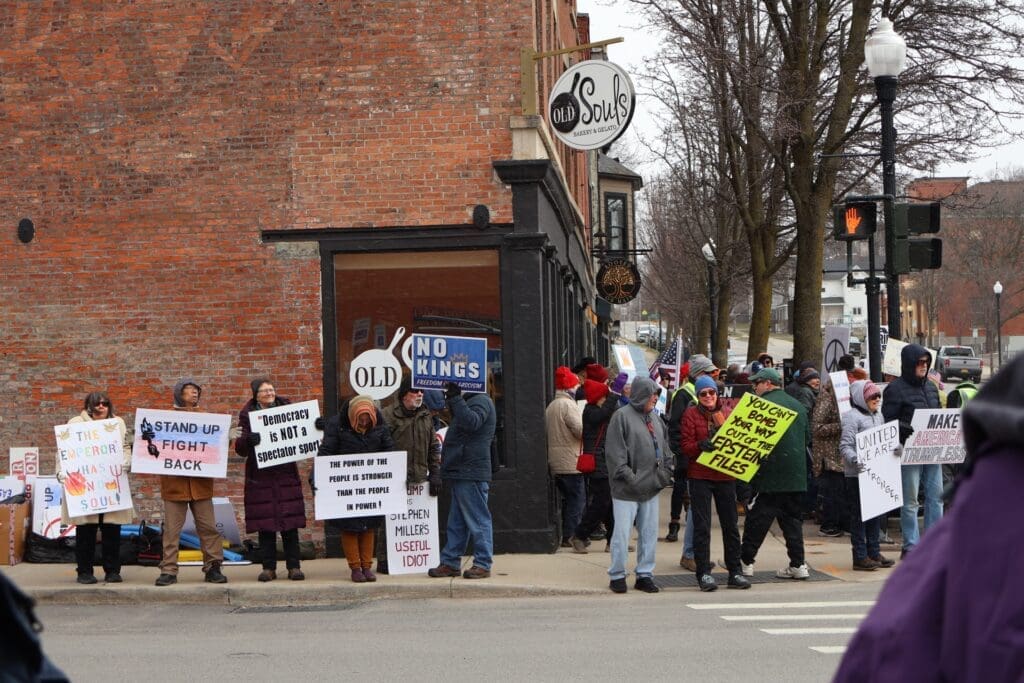 Protesters holding political signs on downtown street corner