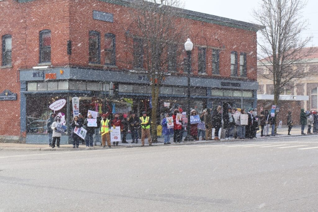 Protesters holding signs outside bookstore during snowfall