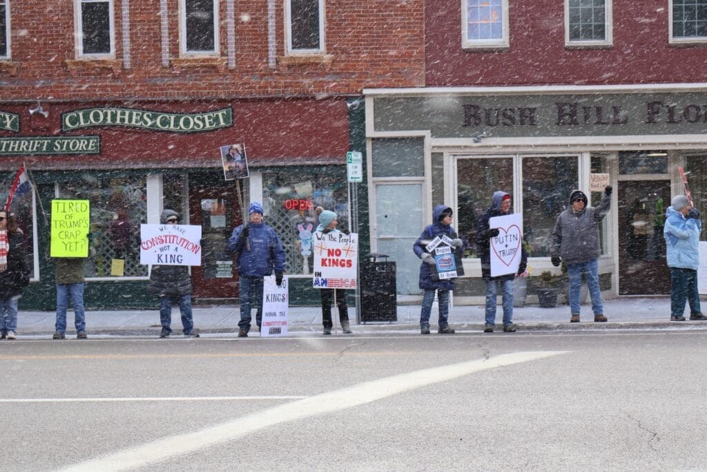 Protesters holding anti-Trump signs in snowy downtown street