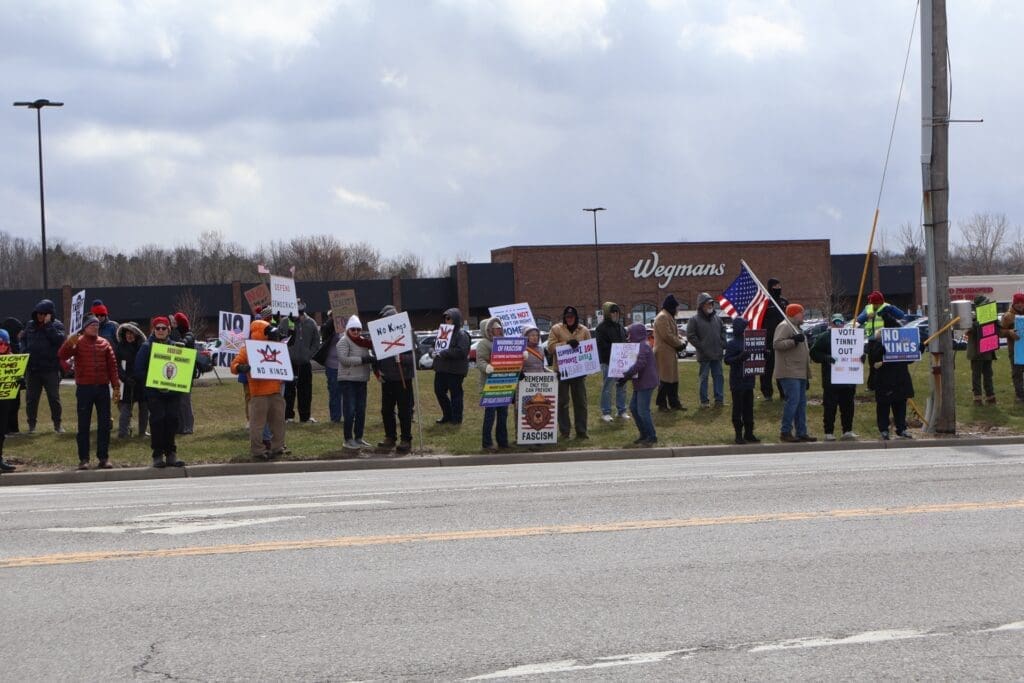 Protesters holding signs and American flag outside Wegmans