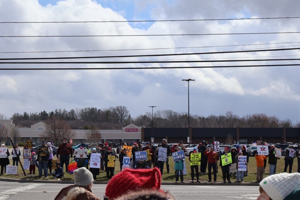 Protesters holding signs along roadside near shopping center