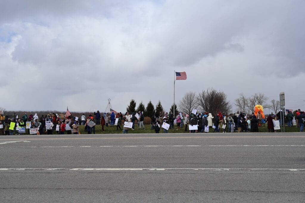 Roadside protest with American flag and crowd