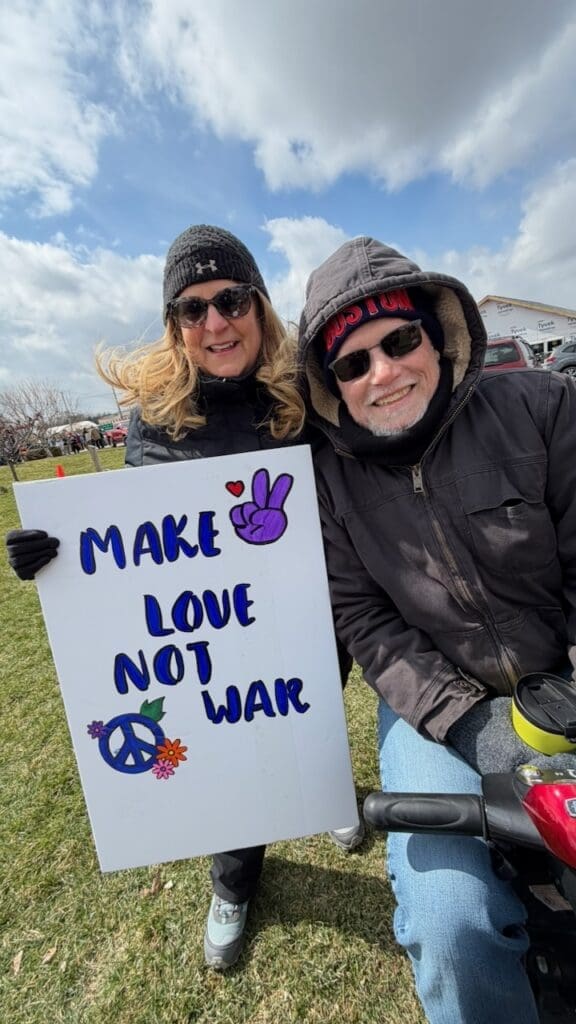 Couple holding 'Make Love Not War' sign outdoors