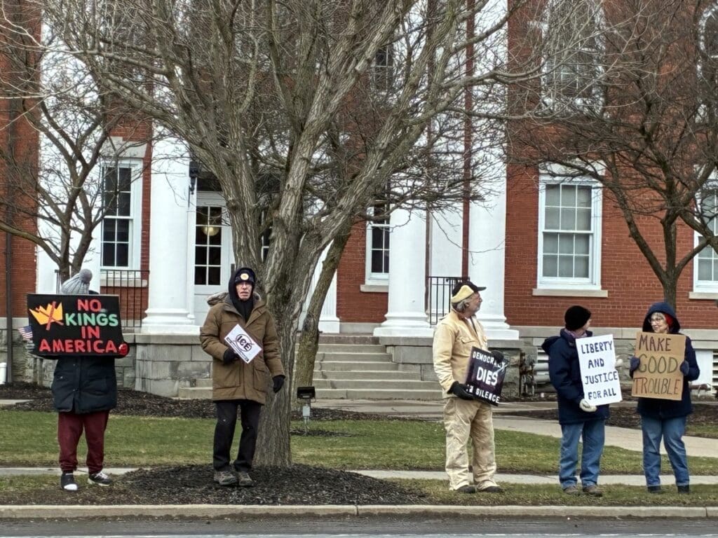 Protesters holding signs outside brick government building