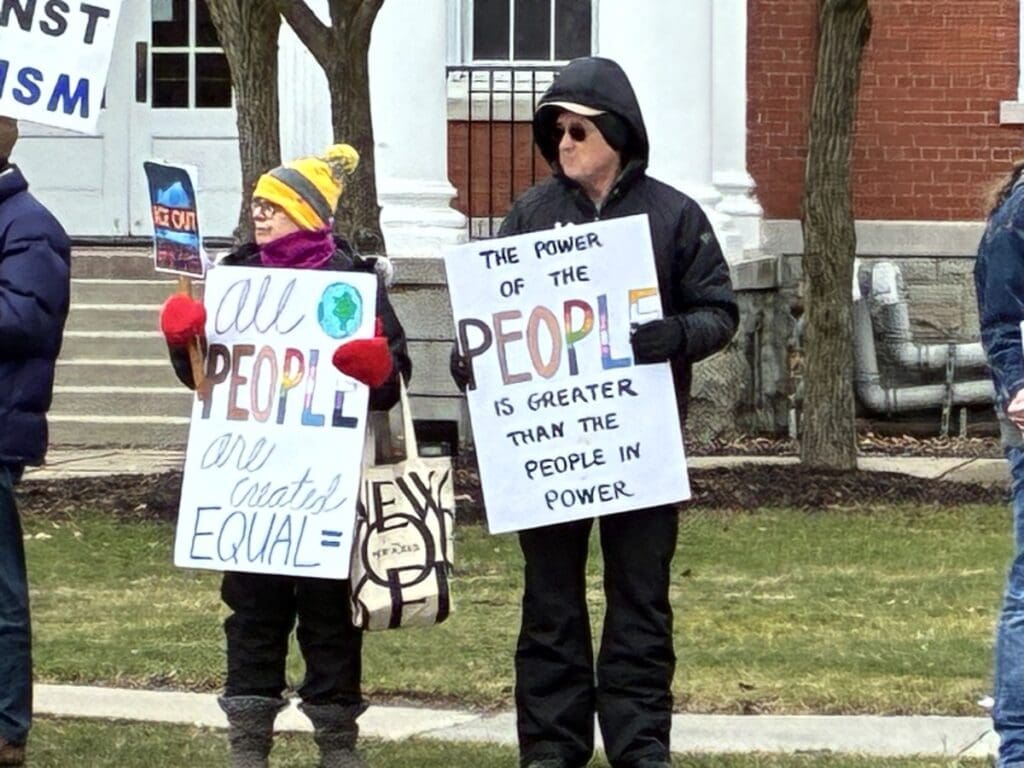 Two protesters holding equality and democracy signs outdoors