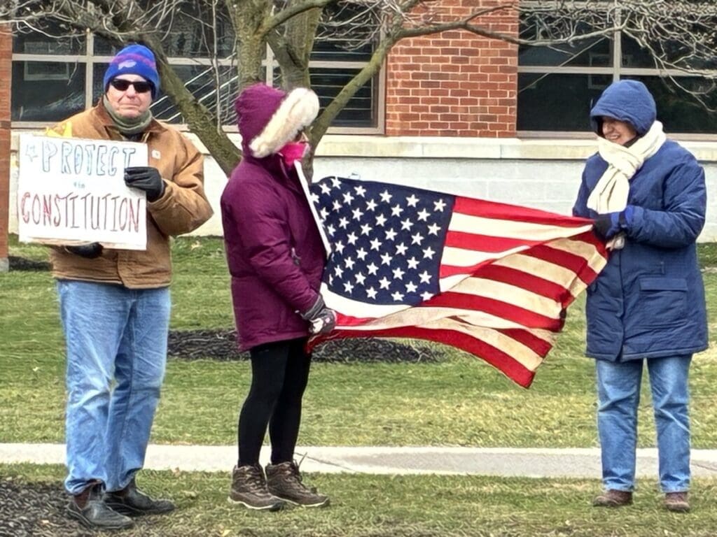 Protesters holding American flag and Protect Constitution sign