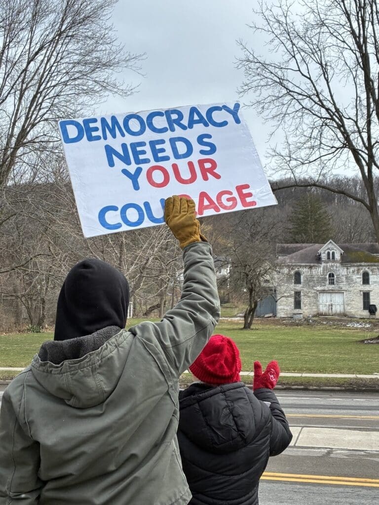 Protesters holding Democracy Needs Your Courage sign