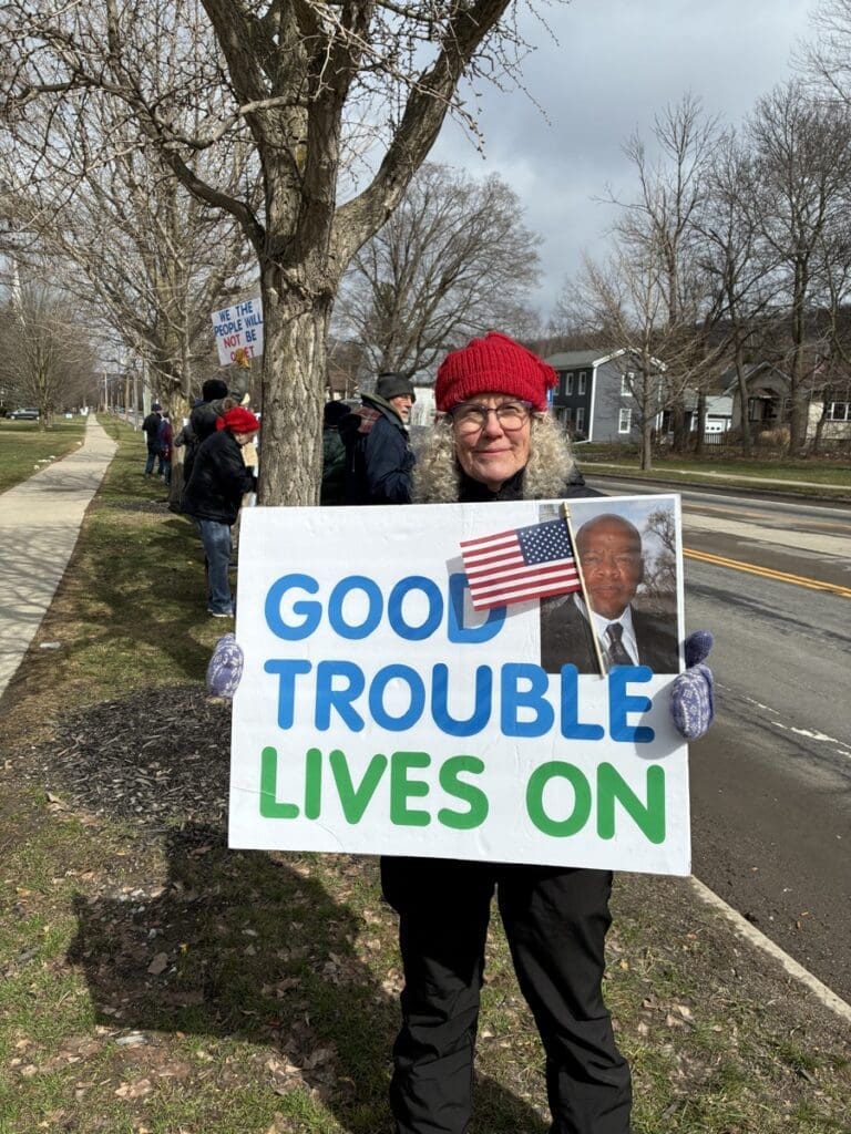 Woman holding Good Trouble Lives On protest sign