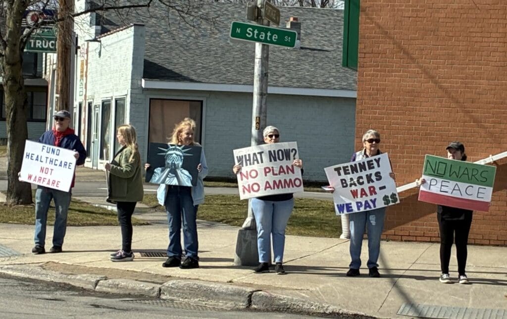 Protesters holding anti-war and healthcare signs roadside
