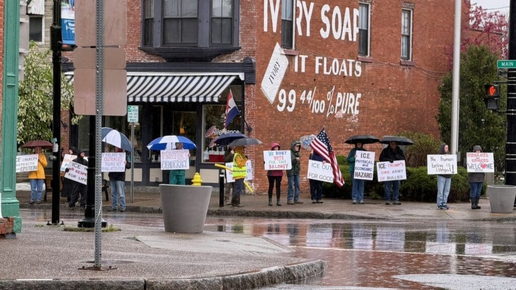 Protesters with signs standing in rain downtown