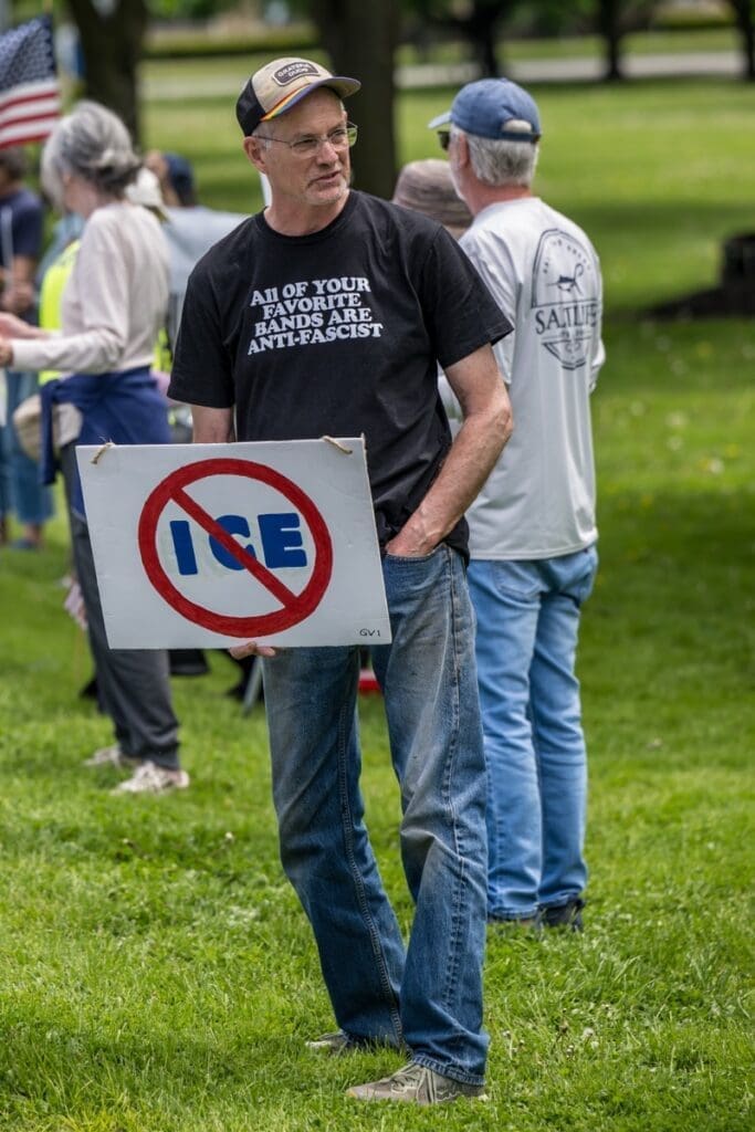 Man holding anti-ICE protest sign in park
