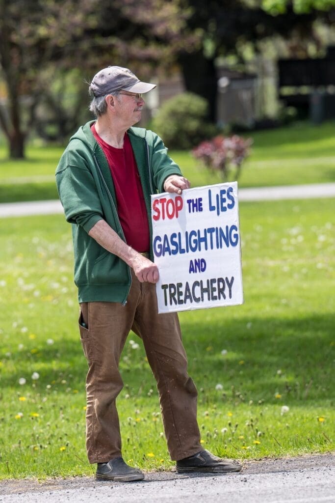 Man holding "Stop the Lies" protest sign