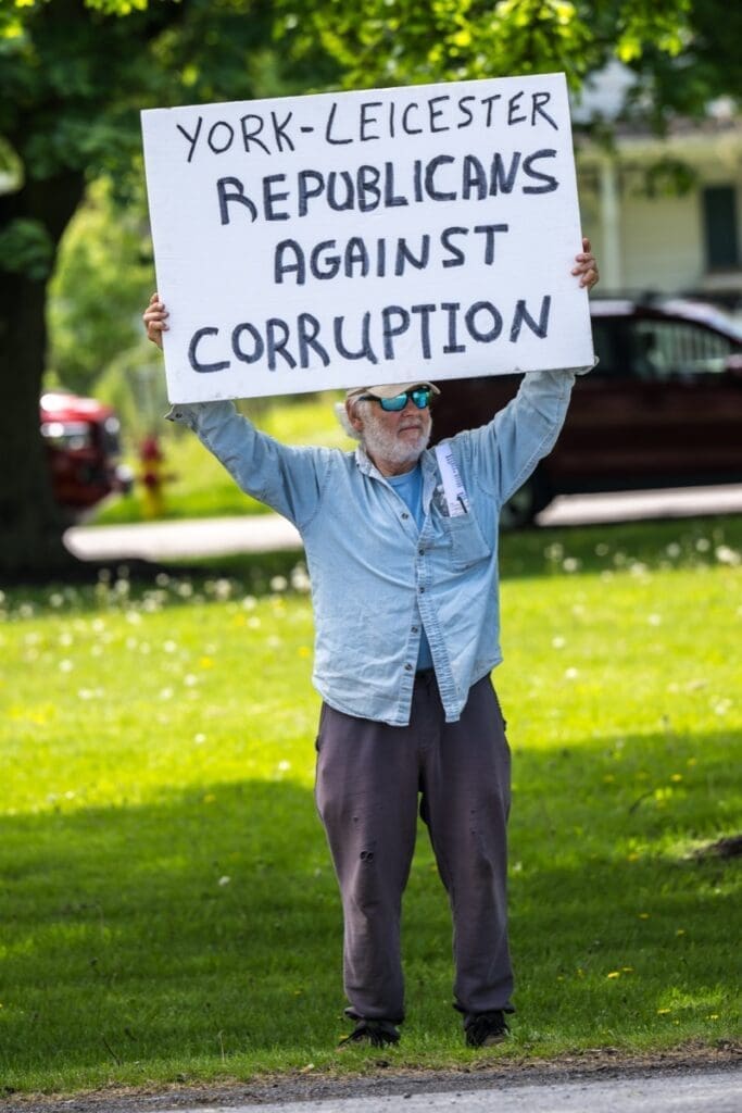 Man holding anti-corruption Republican protest sign outdoors