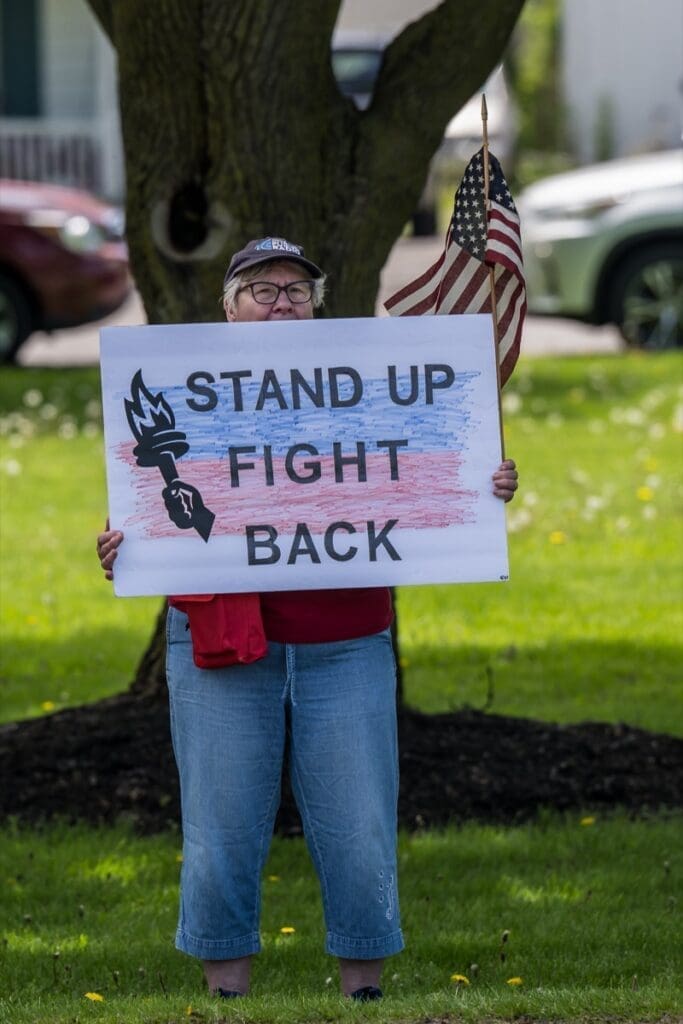 Person holding 'Stand Up Fight Back' protest sign