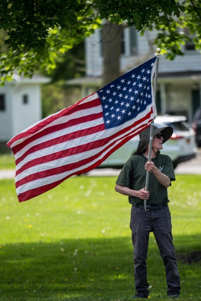 Person holding American flag in suburban yard
