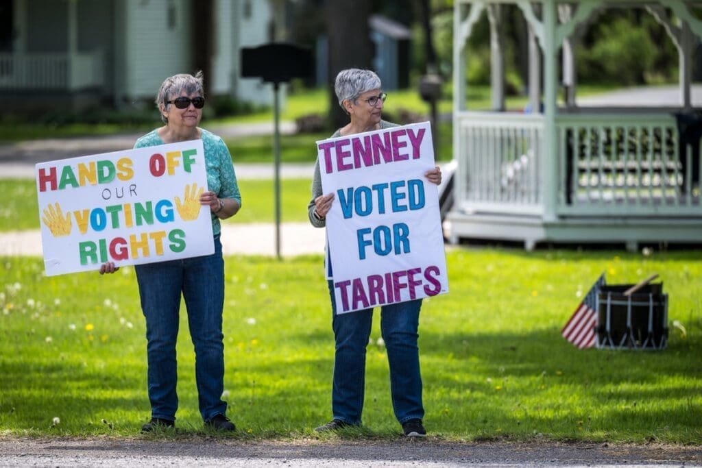 Two women holding voting rights protest signs outdoors