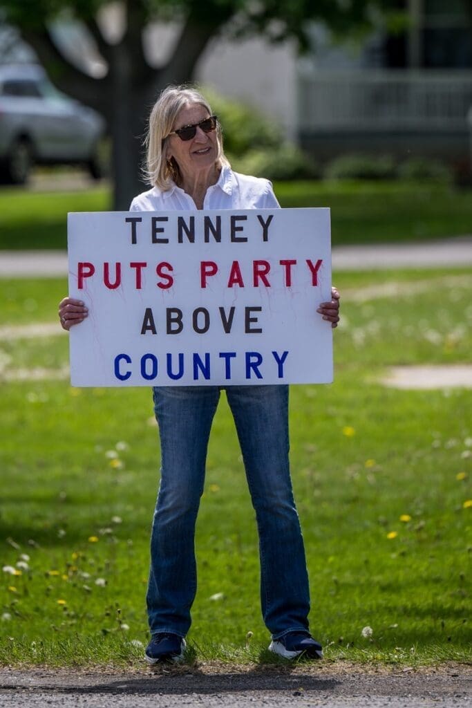 Woman holding 'Tenney puts party above country' sign.