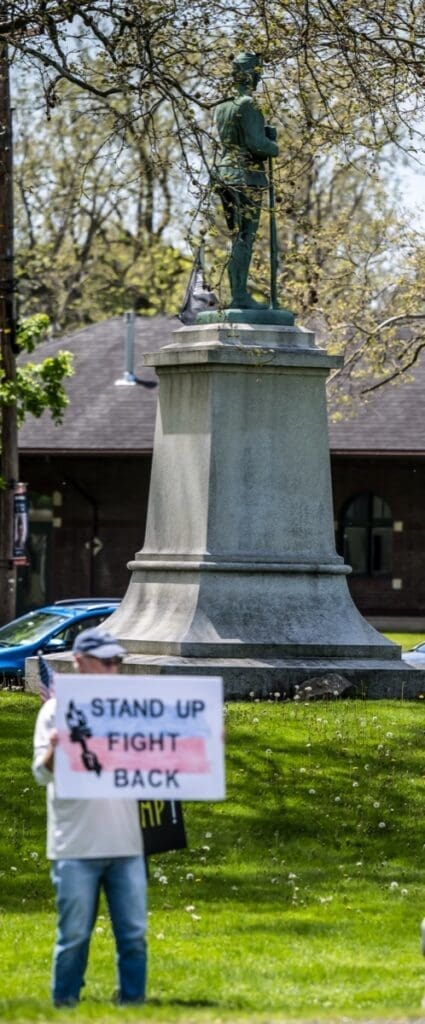 Protester holding sign before statue in park
