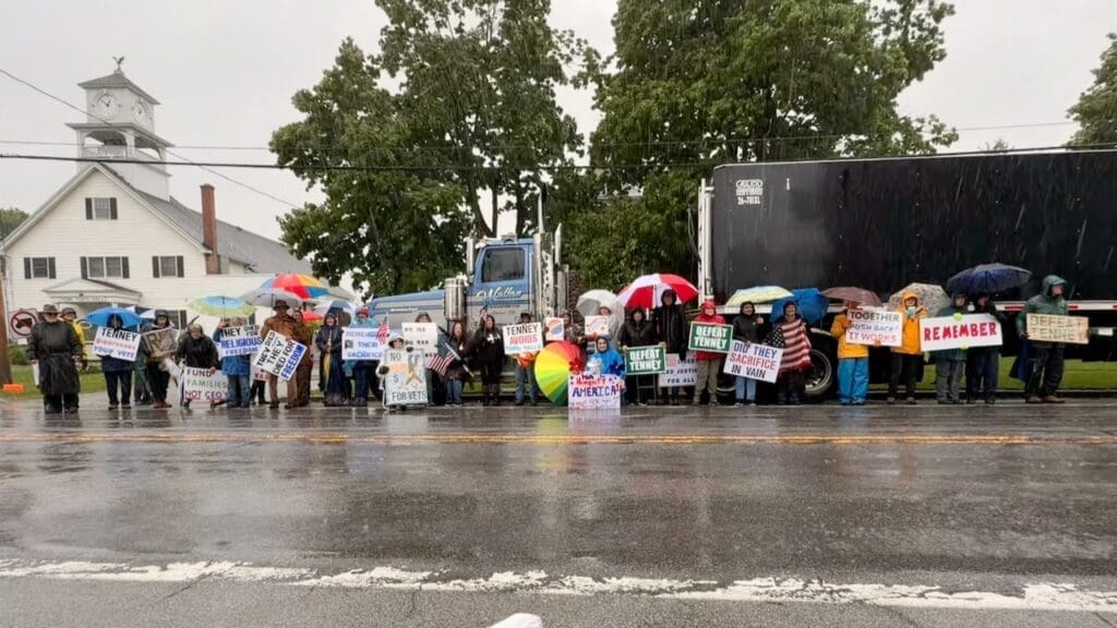 Protesters holding signs in rain outside building
