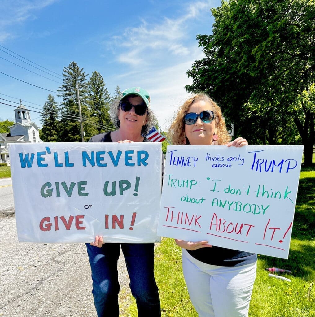 Two women holding political protest signs outdoors
