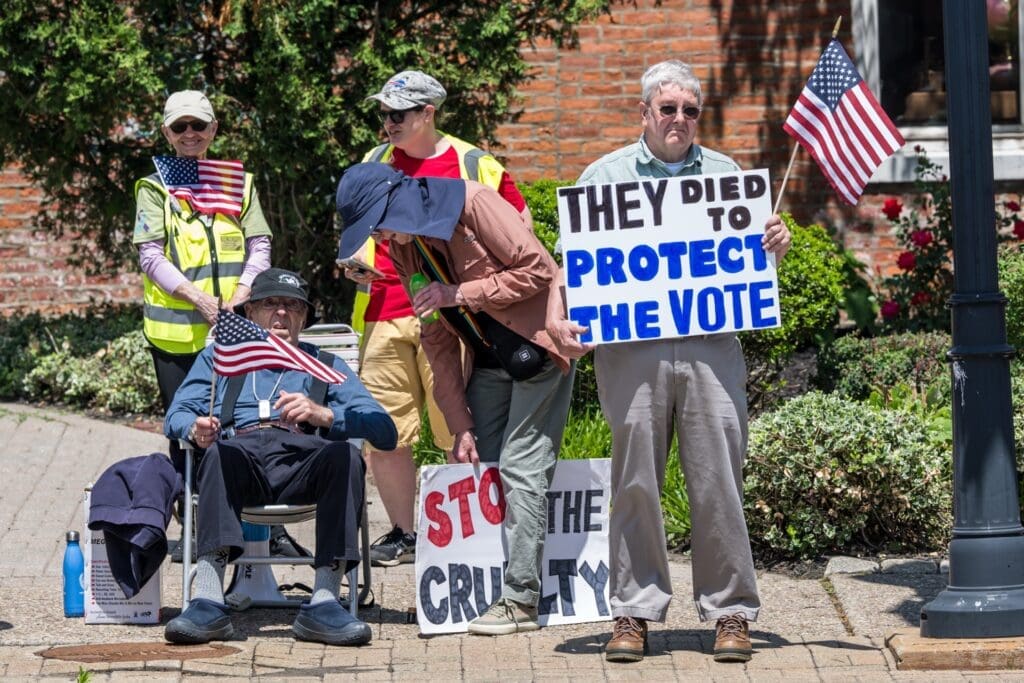 Protesters holding American flags and voting rights signs outdoors